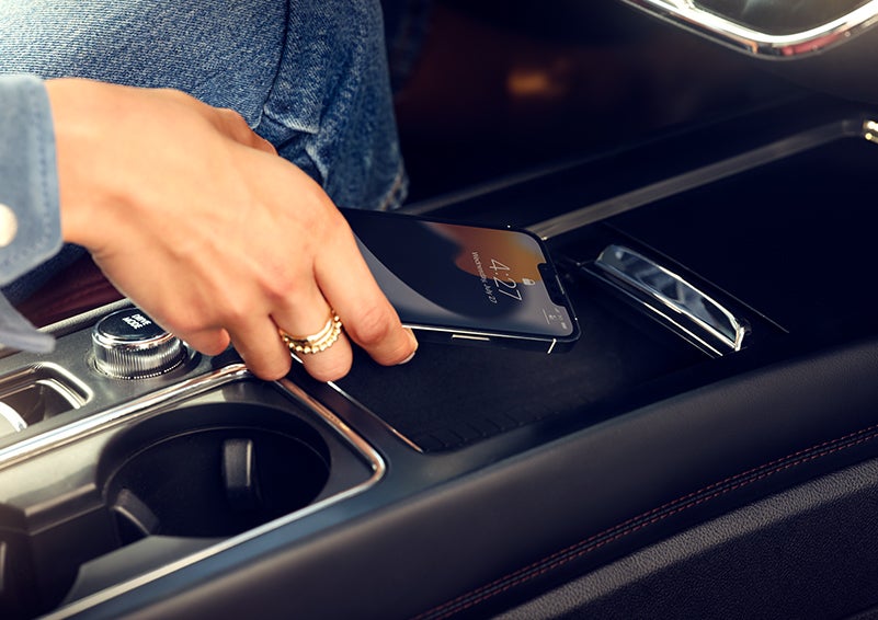 A smartphone is is being placed on the wireless charging pad in the front center console cubby. | Lincoln of Cutler Bay in Miami FL
