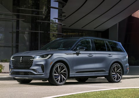 A gray 2025 Lincoln Aviator® SUV is parked outside a modern building showcasing the driver’s side of the vehicle. | Lincoln of Cutler Bay in Miami FL