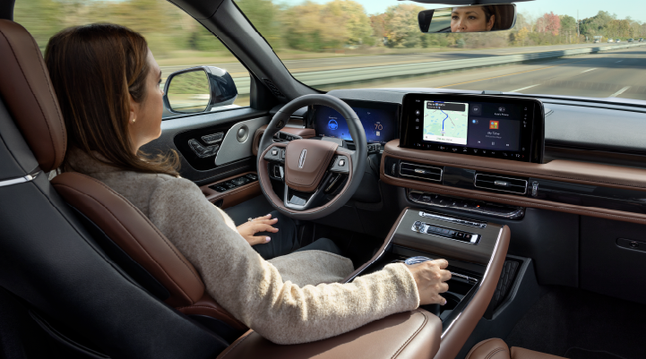 A woman is seen sitting in the driver’s seat of her 2025 Lincoln Aviator® SUV with her hands off the steering wheel. | Lincoln of Cutler Bay in Miami FL